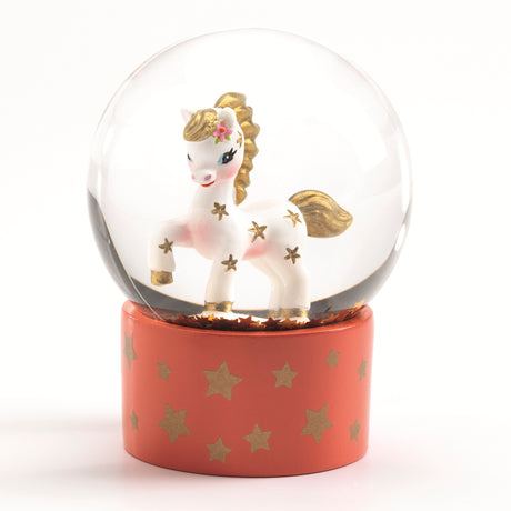 Djeco mini snow globe with a white horse, gold stars, and pink floral detail on an orange base with gold stars.