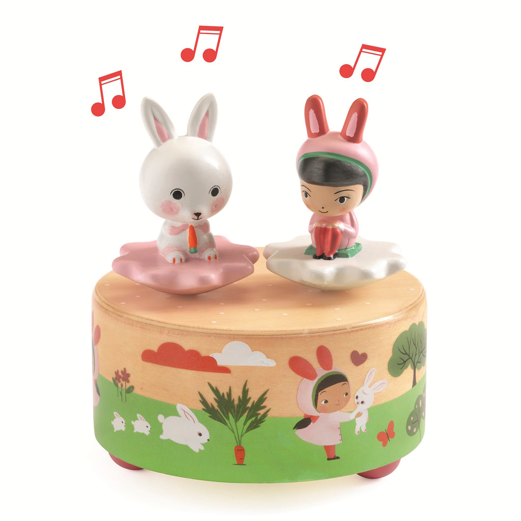 This wooden music box features a whimsical garden scene with removable figurines - a rabbit and a squirrel - that dance and spin on a magnetic top when the box is wound up.