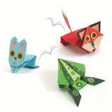A craft kit featuring colorful paper designs and folded animal shapes like frogs and kangaroos that can hop when pressed.
