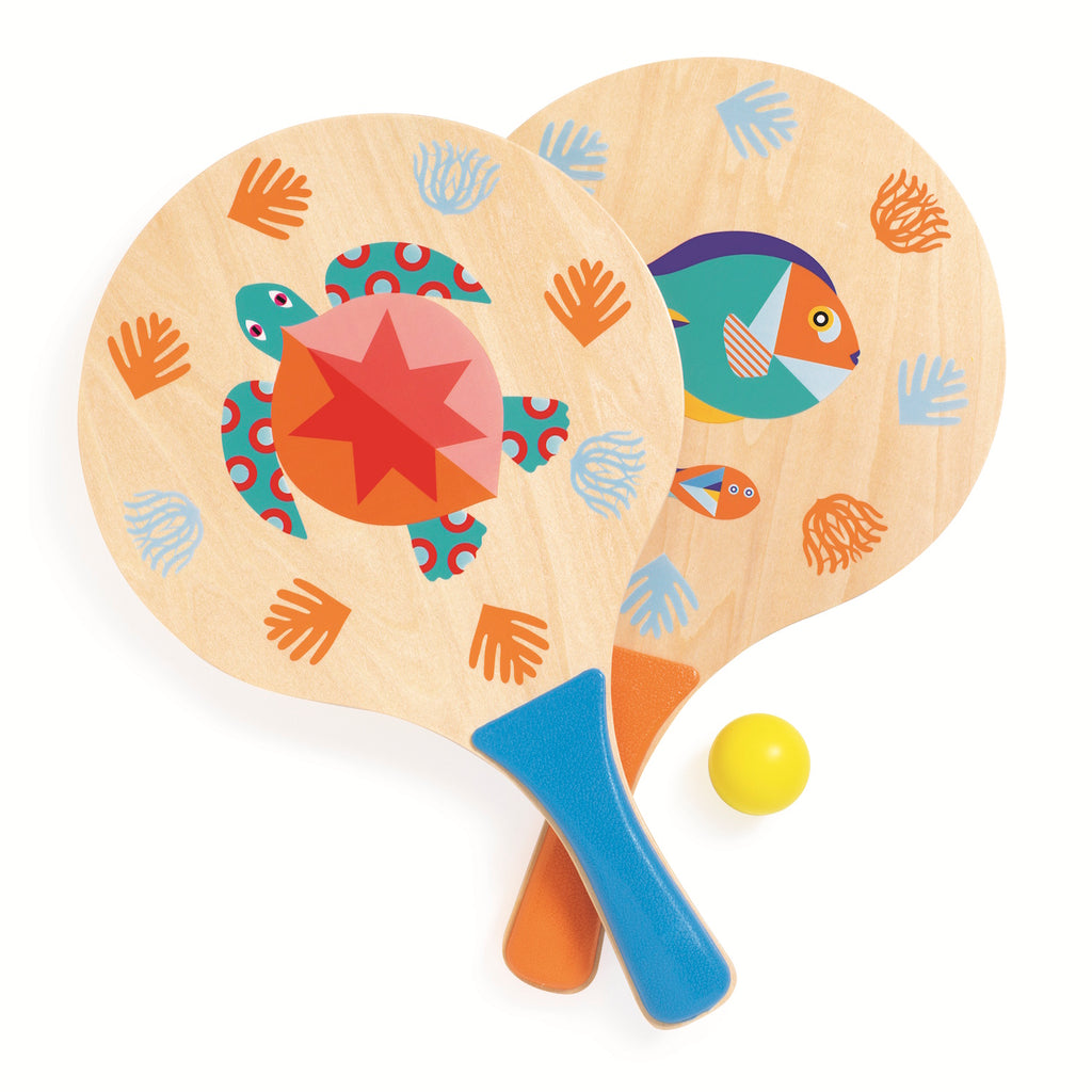 Two playful wooden paddles feature vibrant animal designs with turtles and fish, paired with colorful handprints, beside a bright yellow ball.