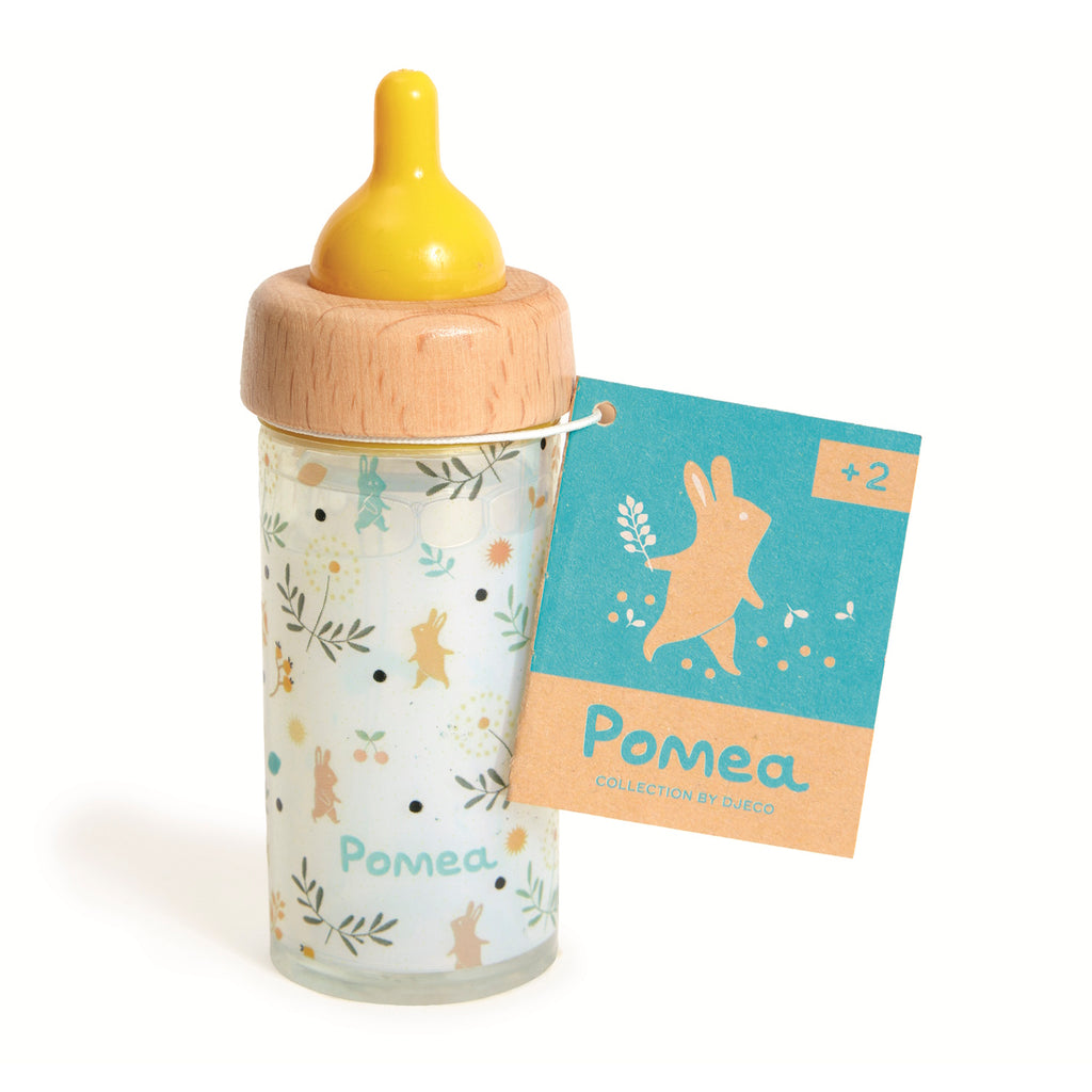 A toy baby bottle with a wooden cap, yellow rubber nipple, and playful animal designs. It has a tag with a bunny graphic and the text "Pomea, +2."