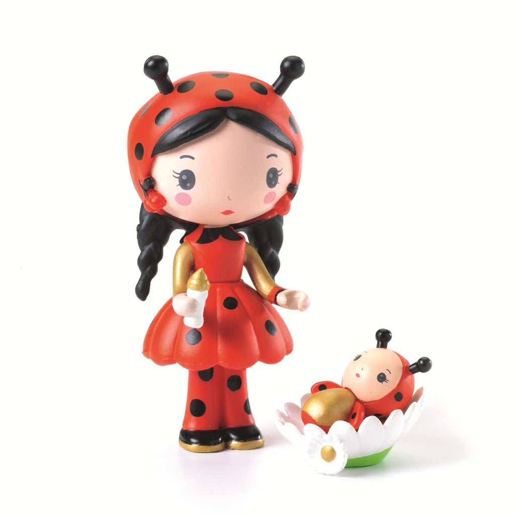 Cute figurines depict a girl and baby in ladybug costumes. The girl holds a bottle, while the baby rests in a flower. Whimsical and playful tone.