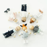 Seven wooden dollhouse family figures lying in a circle with heads pointing toward the center.