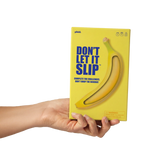 Hand holding the yellow "Don't Let It Slip" game box against a white background.