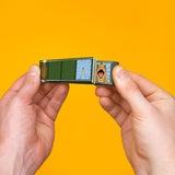 Hands holding a dinosaur flip book against a bright yellow background, showing two animation frames.