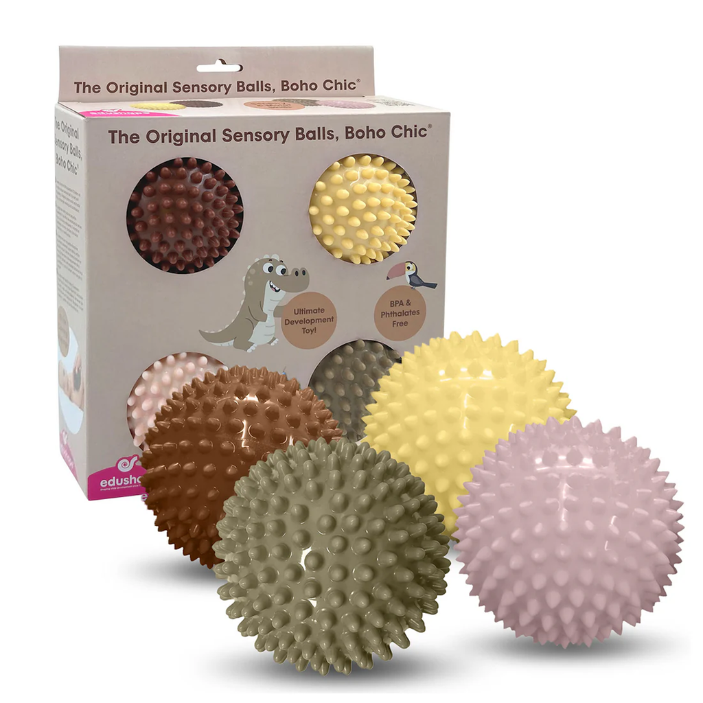 Four textured sensory balls in brown, beige, yellow, and pink are displayed outside a box labeled "The Original Sensory Balls, Boho Chic." Kid-friendly packaging with playful animal illustrations conveys a fun, developmental toy.