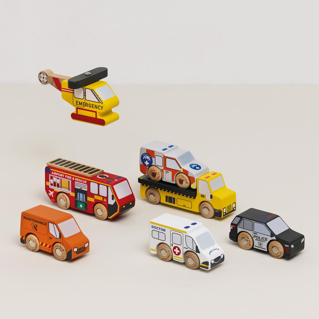 Toy wooden vehicles, including a yellow emergency helicopter, fire truck, maintenance van, dump truck, police car, ambulance, and rescue vehicle, each with colorful details.