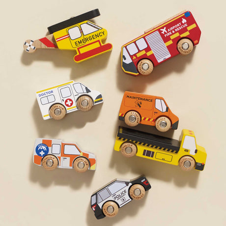 Overhead view of a seven-piece wooden toy emergency vehicle set arranged on a beige background.