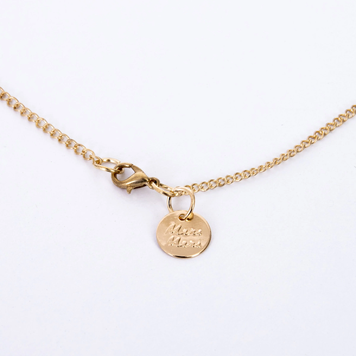 Gold-tone necklace clasp and chain featuring a small round charm with the Meri Meri brand logo.