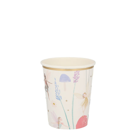 A paper party cup with a gold rim, decorated with illustrations of fairies, mushrooms, and flowers.