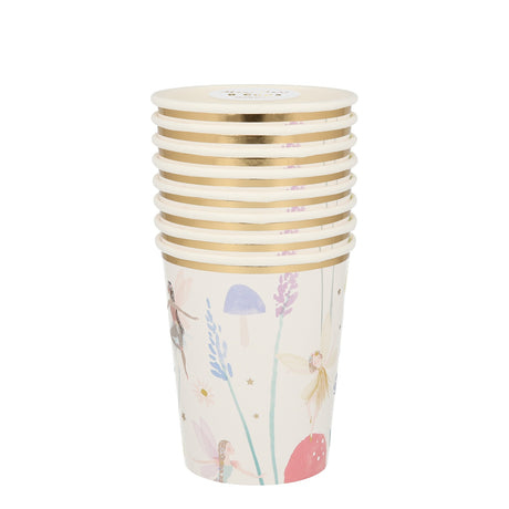 A stack of white paper cups with gold rims, illustrated with fairies, mushrooms, and flowers.