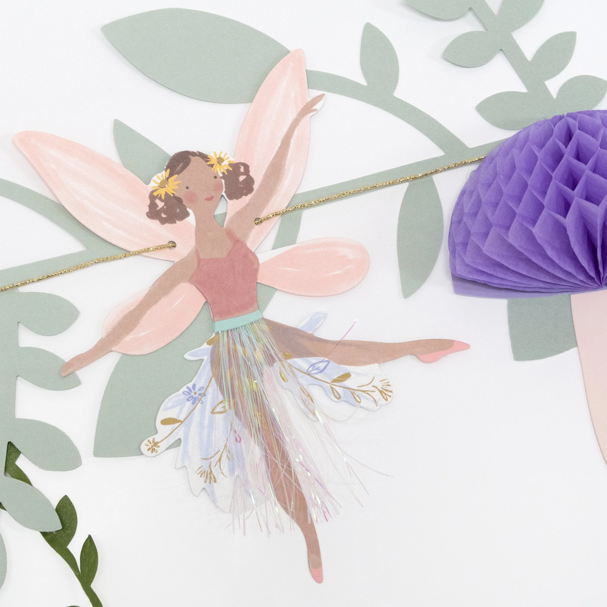 Detailed shot of a fairy garland cutout with pink wings, tinsel skirt details, and a purple honeycomb mushroom.