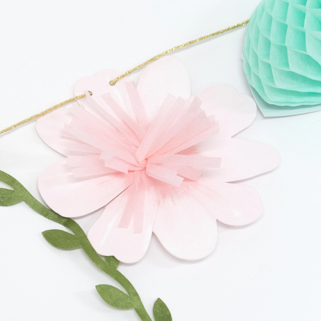 Close-up of a fairy garland featuring a soft pink paper flower with a fringe center and mint honeycomb detail.