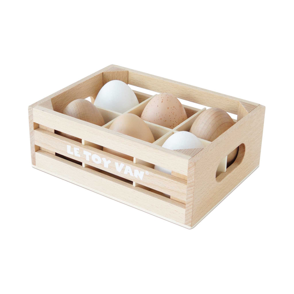 Wooden crate labeled "LE TOY VAN" holding five toy eggs in white, tan, and speckled brown.
