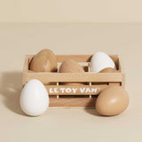 Wooden crate filled with toy eggs on a beige background.