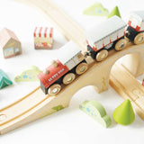 Wooden toy train crossing over an elevated wooden bridge with small scenery pieces around.
