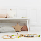 Wooden toy train set assembled in a figure-of-eight track with a bridge, cars, and scenery.