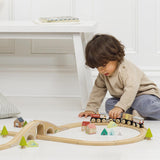 Young child playing with a wooden toy train set on the floor.
