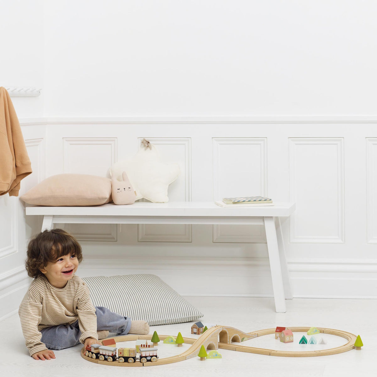 Toddler playing on the floor with a figure-of-eight wooden toy train set.