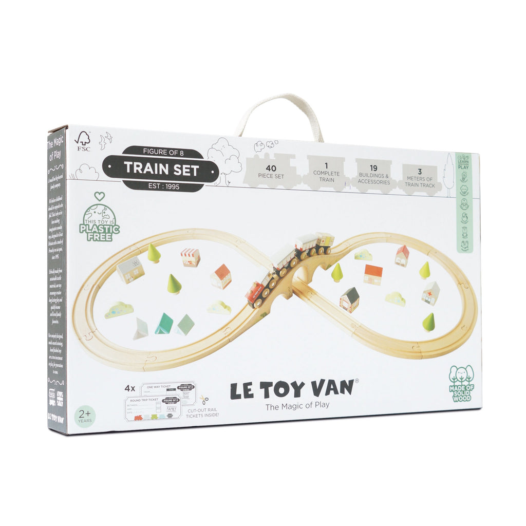 Box for "Le Toy Van" train set featuring a wooden figure-eight track, colorful trains, and accessories. Labels highlight it's plastic-free and made from solid wood.