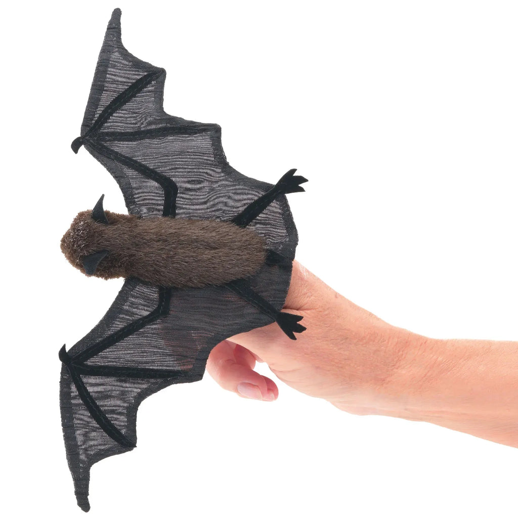 A hand holds a realistic brown bat finger puppet. The bat has detailed, spread-out black wings. The puppet conveys a playful and whimsical tone.