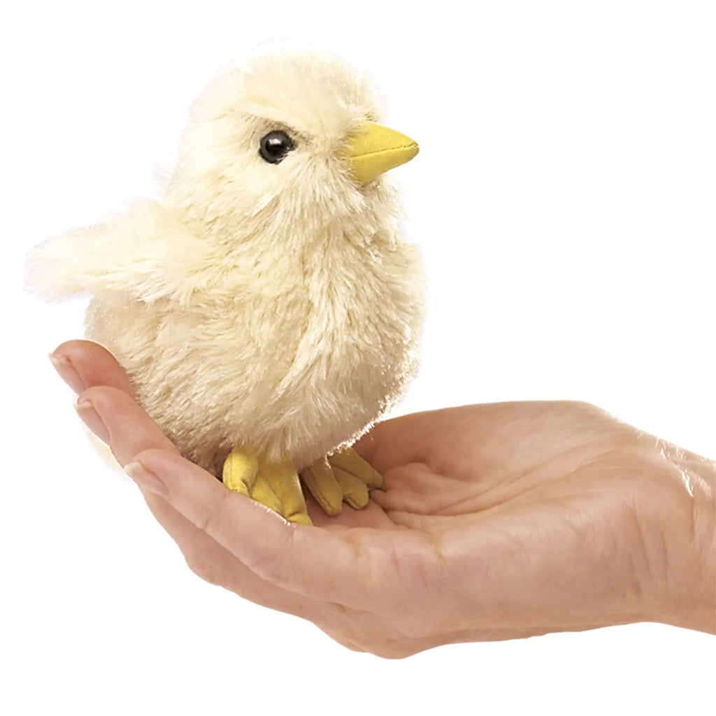 A realistic plush chick with soft, fluffy yellow feathers and a bright yellow beak sits in an open hand, conveying warmth and care.