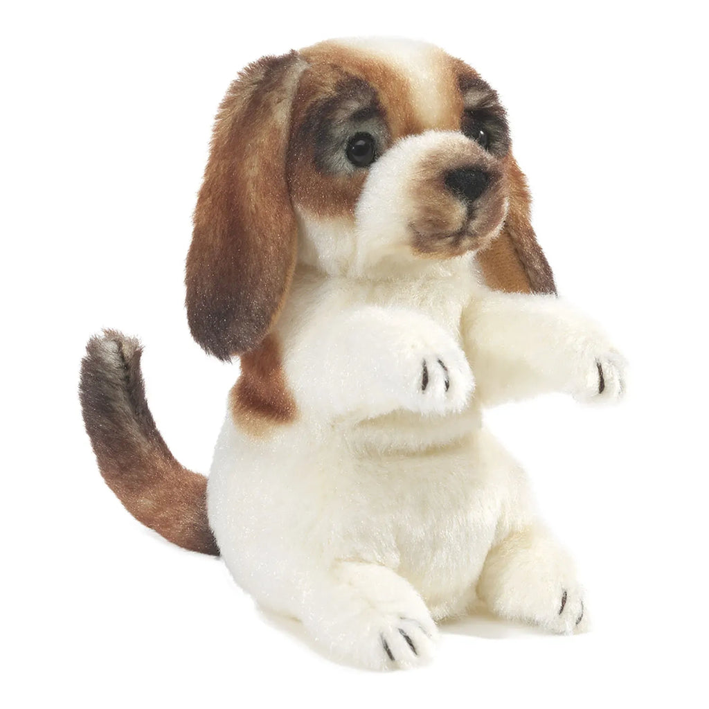 A plush toy resembling a sitting beagle puppy with floppy ears. Its fur is a mix of white and brown, giving it a lifelike, cute appearance.