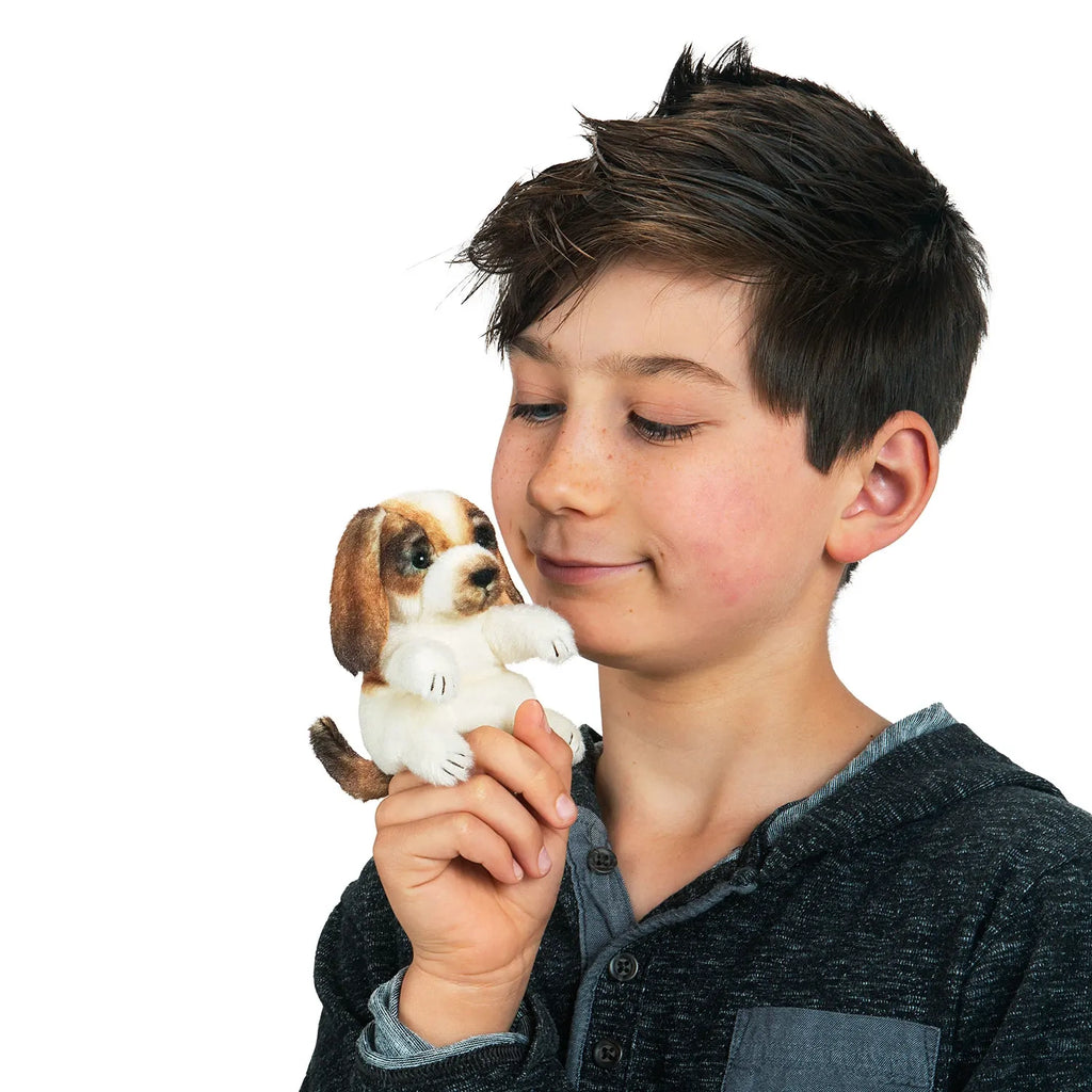 A plush toy resembling a sitting beagle puppy with floppy ears. Its fur is a mix of white and brown, giving it a lifelike, cute appearance.