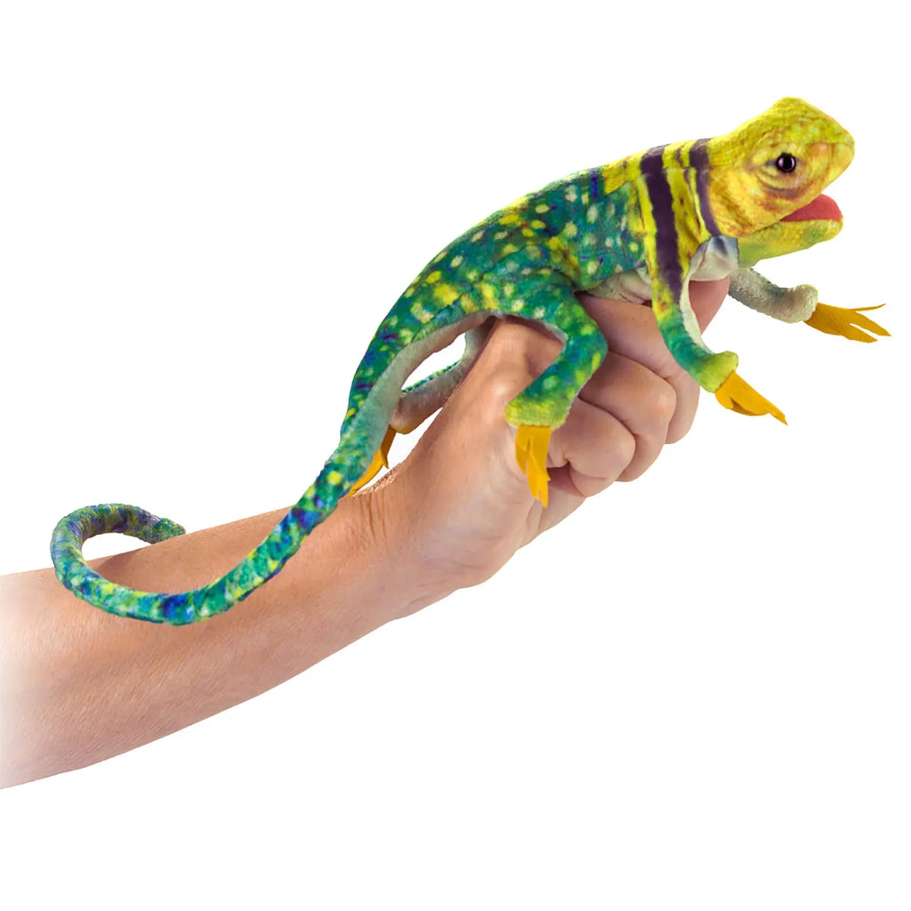 A colorful, plush toy lizard with green, yellow, and blue patterned skin is playfully wrapped around a person's hand. The tone is playful and whimsical.