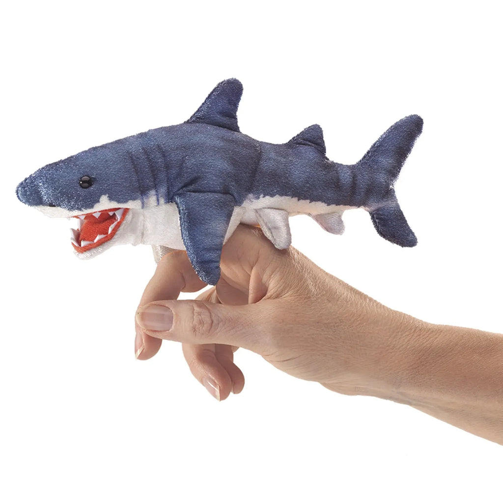 A hand is shown wearing a blue and white plush shark finger puppet. The shark has an open mouth with visible red and white felt teeth, creating a playful tone.