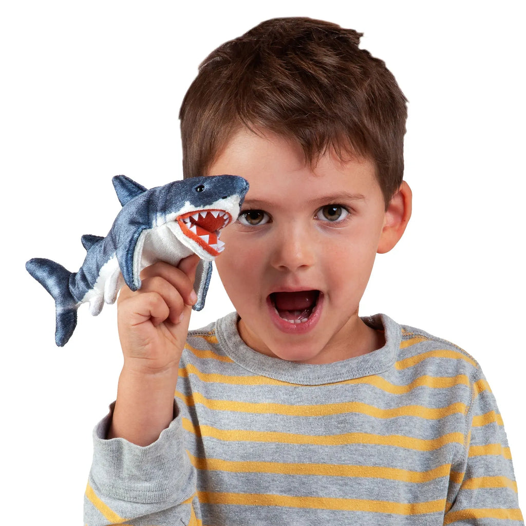 Young boy in a striped shirt holding a plush shark toy near his face, mouth open wide in excitement, creating a playful and joyful atmosphere.