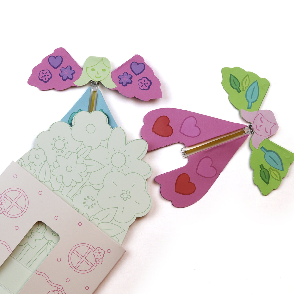 Two colorful paper fairy figures with wire mechanisms next to an illustrated craft envelope.
