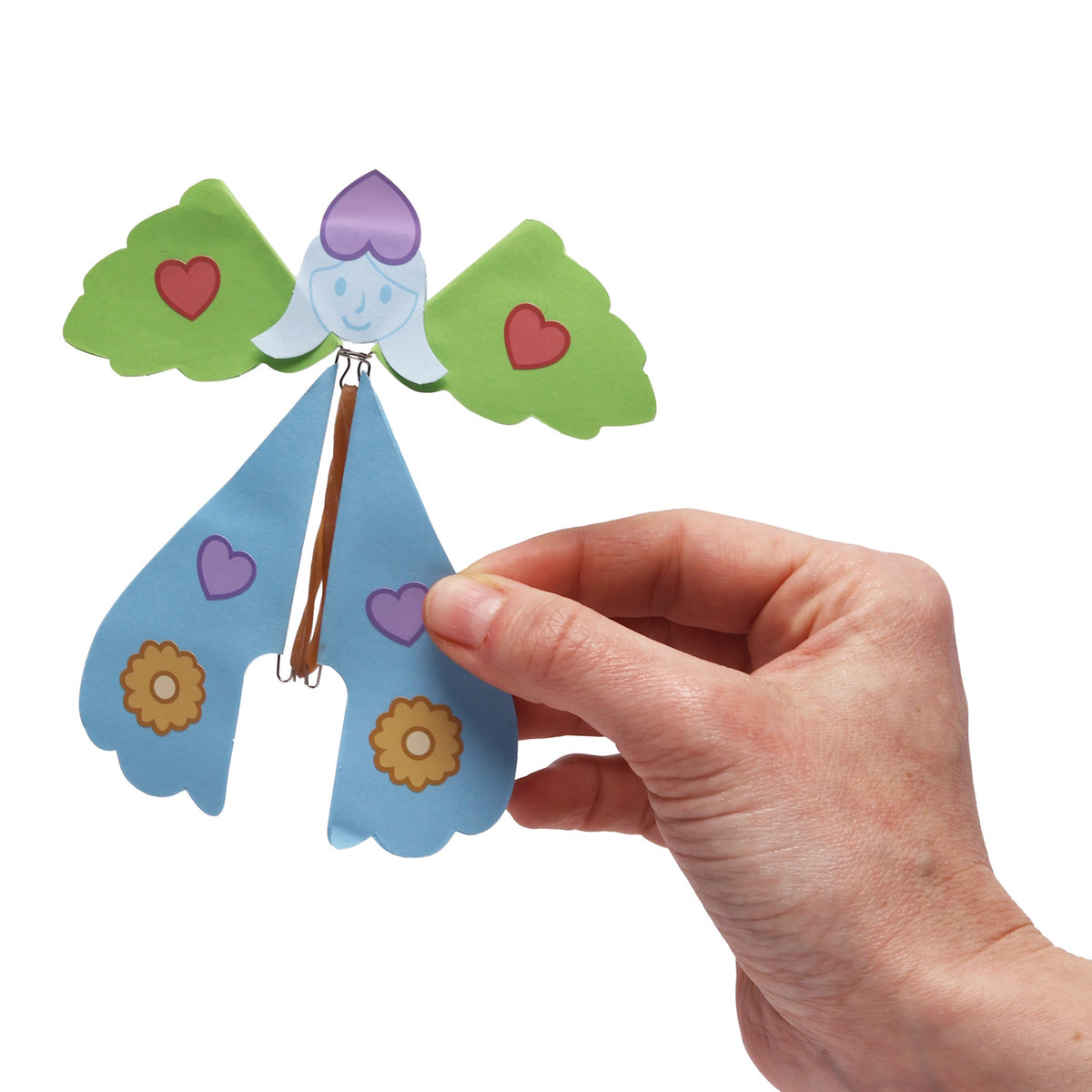 A hand holding a colorful paper fairy craft with green wings and a blue body.