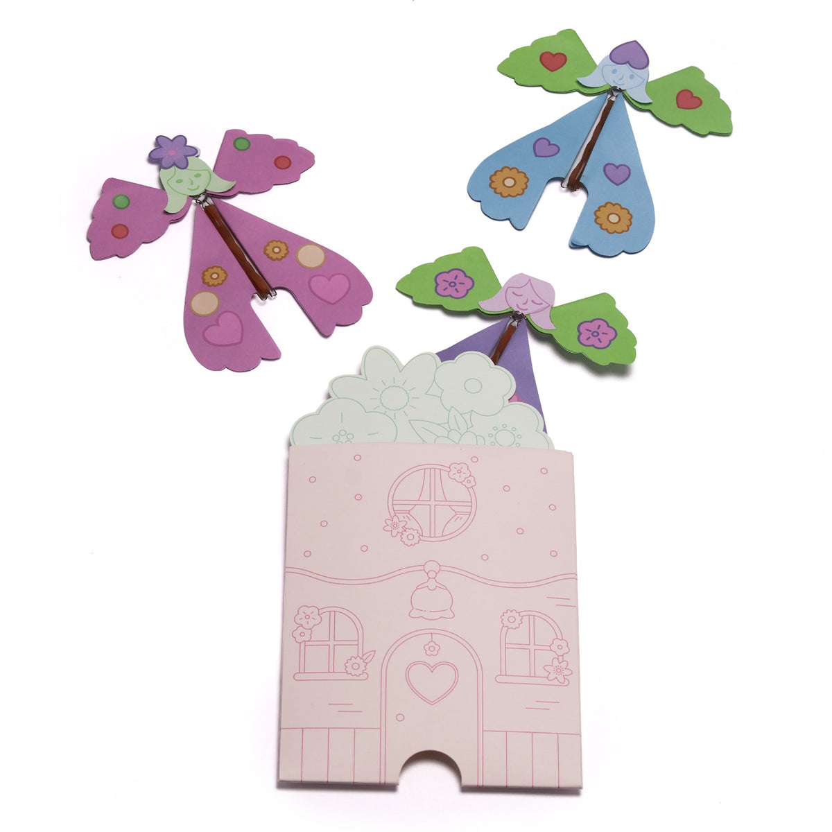 Three colorful paper fairies flying above an illustrated pink house envelope.