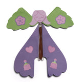 Assembled purple paper fairy toy with green wings and rubber band flying mechanism.