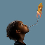 Child blowing into a straw to launch a yellow paper rocket into the air.