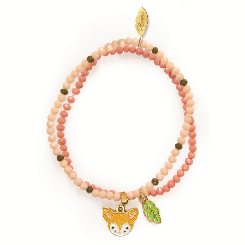 Beaded pink bracelet featuring green and brown beads, with gold charms of a fox face and leaf. The tone is playful and whimsical.