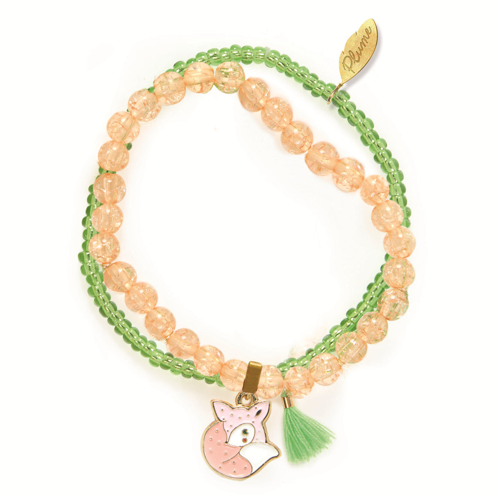 Two beaded bracelets with pink and green beads. A gold charm of a fox and a small green tassel hang from the pink beads, conveying a playful tone.
