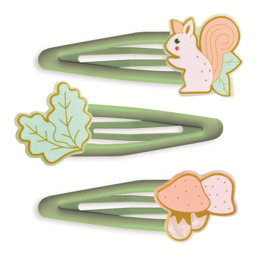 Three green hair clips adorned with playful illustrations, a squirrel, an oak leaf, and two mushrooms. The design evokes a whimsical, nature-inspired theme.