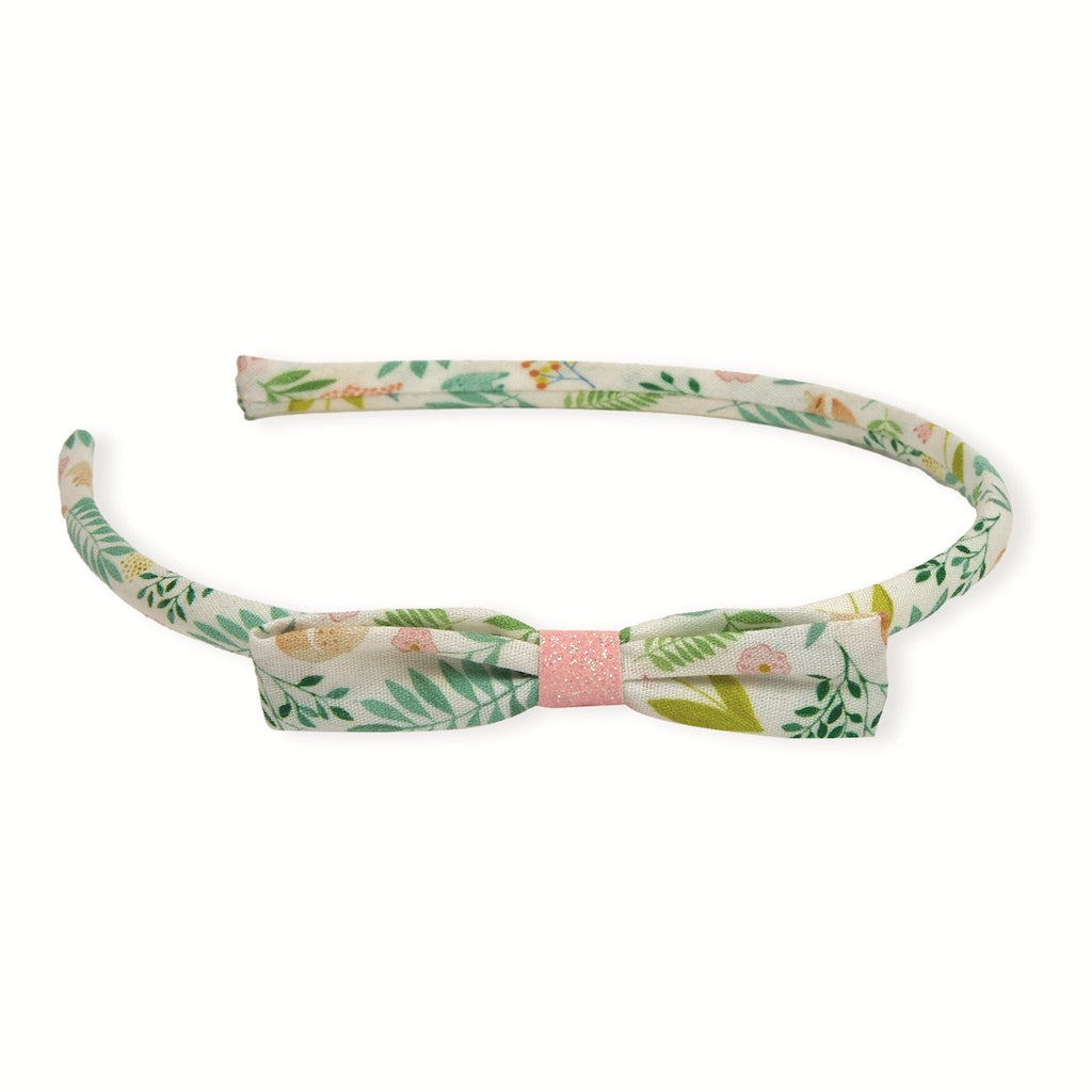 Floral headband with a bow, featuring green and pink leaves. It has a soft and delicate pattern with a pink glittery center accent.
