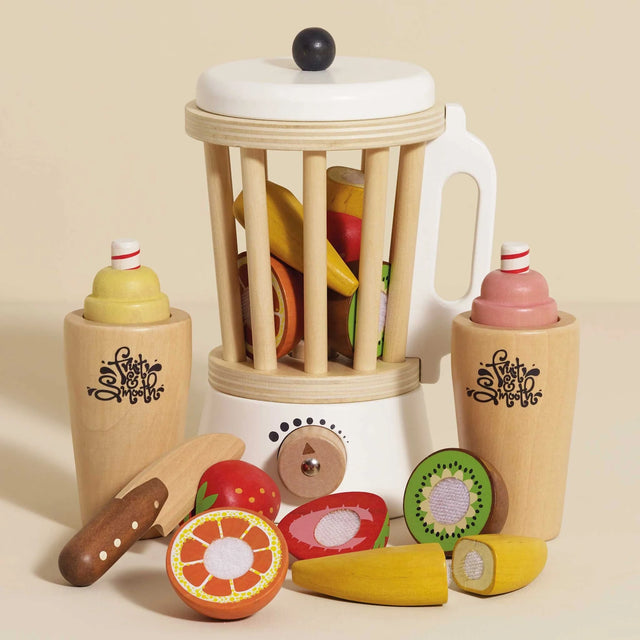 Wooden toy blender set with play fruit pieces, cups, and a toy knife on a neutral background.