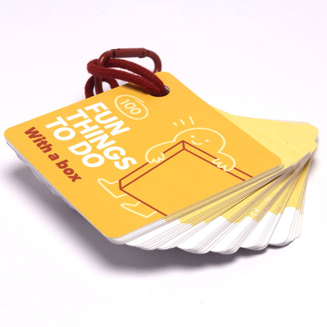 Yellow card deck titled "100 Fun Things To Do With a box" held together by a red binder ring.