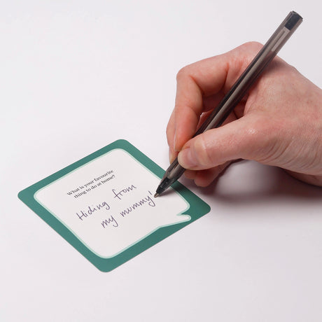 Hand writing a response on a small prompt card with a pen.