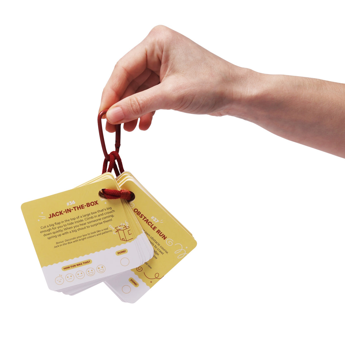 Hand holding a ring of yellow activity cards featuring "Jack-in-the-Box" and "Obstacle Run" prompts.