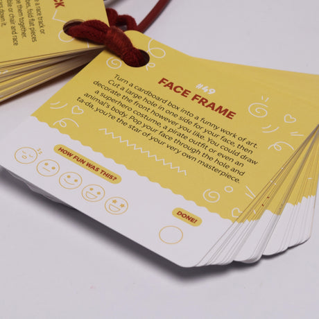 A deck of yellow activity prompt cards bound by a red string showing "Face Frame" activity #49.