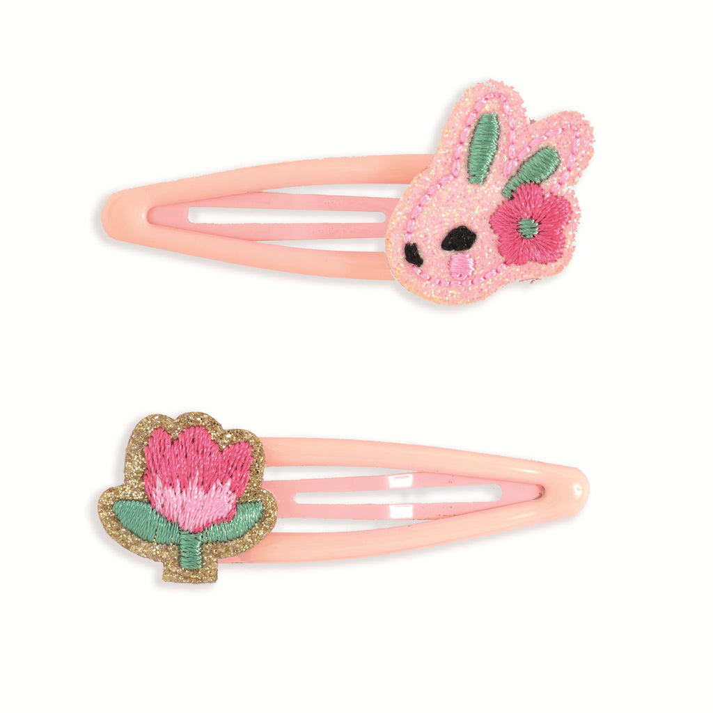 Two pink hair clips are displayed. The top clip features a bunny with green ears and a pink flower. The bottom clip has a pink flower with a green stem.
