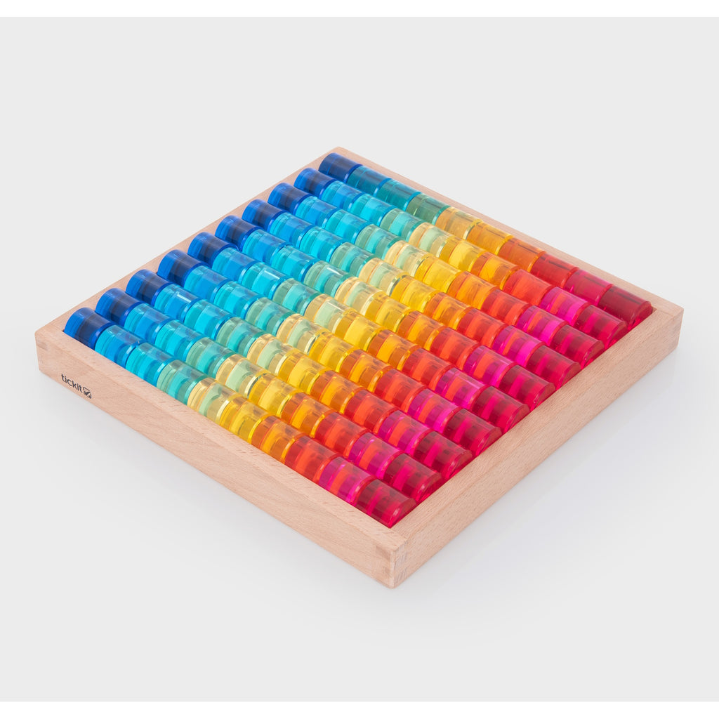 A wooden tray with a mirrored base and colorful gem-like insets, designed for sensory play, loose parts exploration, and visual stimulation.