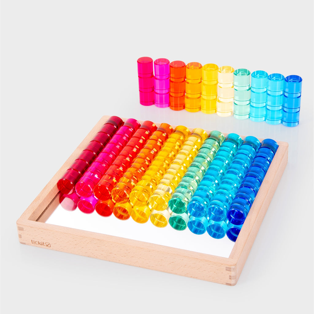 A wooden tray with a mirrored base and colorful gem-like insets, designed for sensory play, loose parts exploration, and visual stimulation.