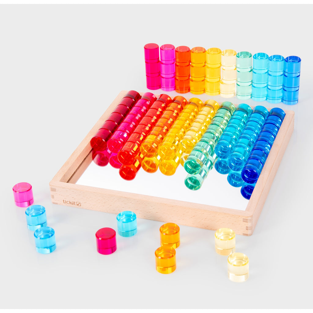 A wooden tray with a mirrored base and colorful gem-like insets, designed for sensory play, loose parts exploration, and visual stimulation.