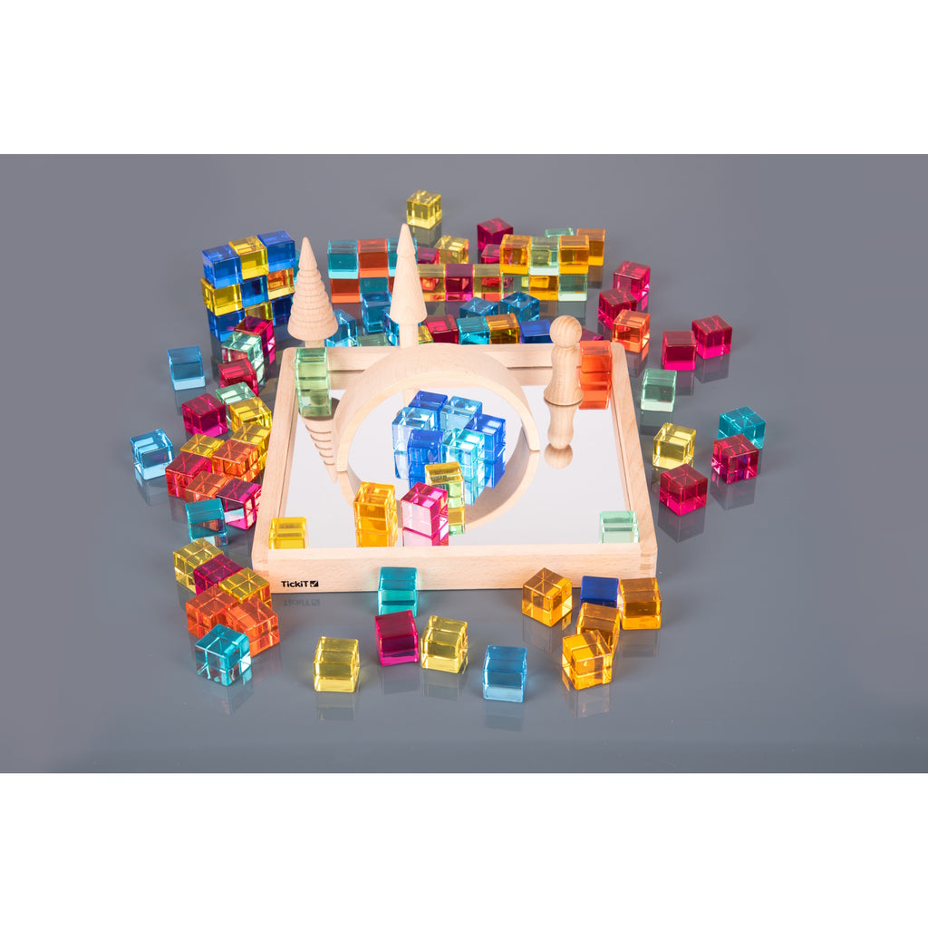 A square wooden tray with a mirrored base and colorful gem-like insets, designed to inspire sensory exploration, pattern making, and visual play.